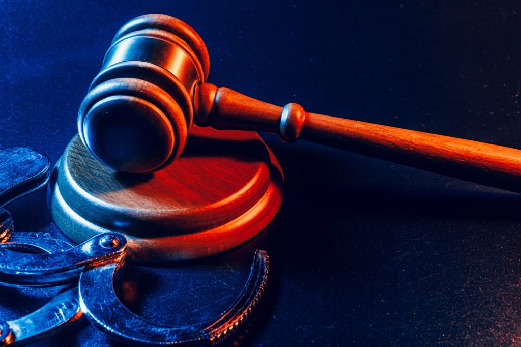 Judge gavel and handcuffs on dark black background